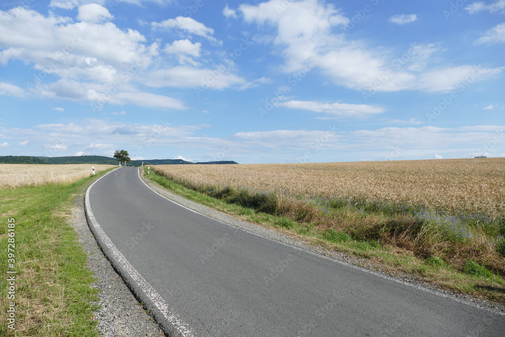 Landstrasse mit reifen Getreidefeldern, Himmel und Wolken Landstrasse mit reifen Getreidefeldern, Himmel und Wolken