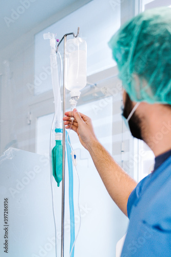 Back view of unrecognizable male anesthetist preparing dropper in operating theater of modern hospital photo