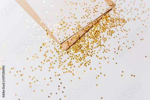 Blank note with envelope and gold glitter stars on white background