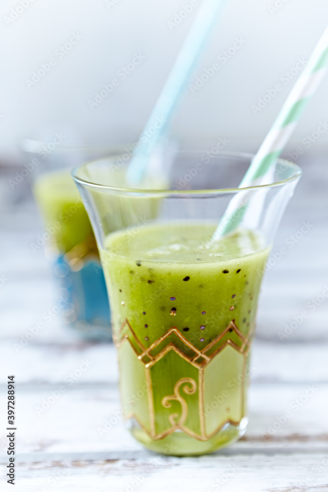 Green smoothie topped with chia seeds on bright wooden background. Close up. Green smoothie topped with chia seeds on bright wooden background. Close up.