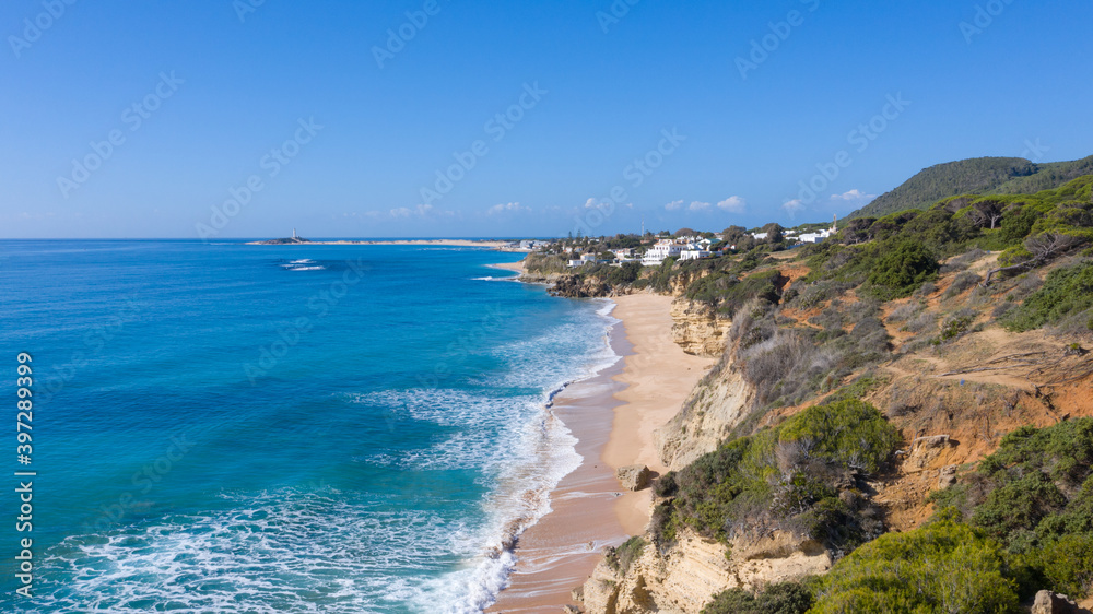 Aerial perspectives of a south Spanish beach in Andalusia with turquoise blue water. Andalusian Atlantic beach background. Ocean in Caños de Meca, Cádiz, Andalusia, Spain. Aerial perspectives of a south Spanish beach in Andalusia with turquoise blue water. Andalusian Atlantic beach background. Ocean in Caños de Meca, Cádiz, Andalusia, Spain.