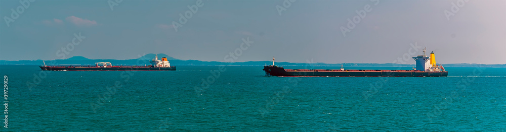A pair of tankers sailing in the Singapore Straits in Asia in summertime