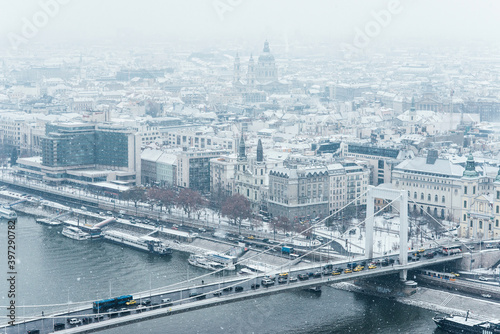 Aerial view of Budapest  Danube river and traffic on the bridge during grey cloudy snowy winter day in December