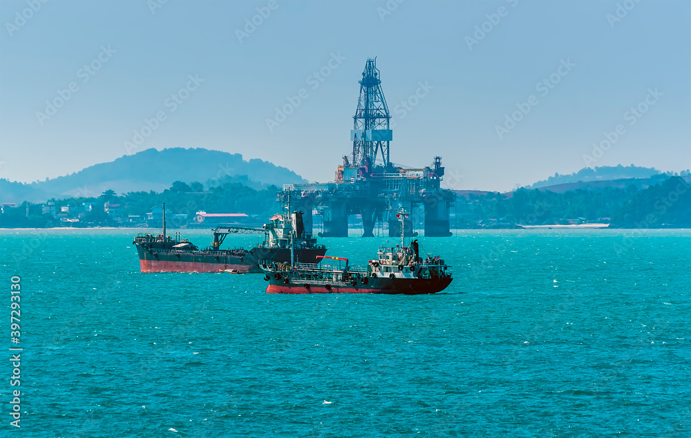 A group of small tankers moored close to a drilling rig in the Singapore Straits in Asia in summertime