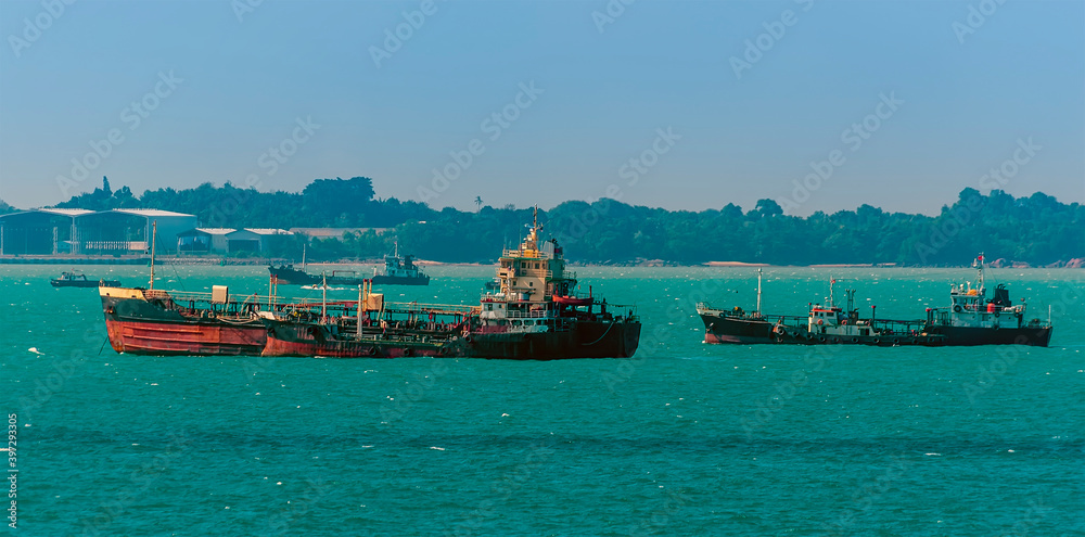A group of small tankers moored offshore in the Singapore Straits in Asia in summertime