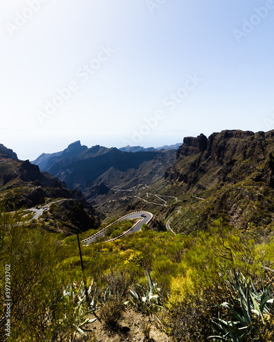 Green mountain hills and winding road with a car driving near Masca village on a sunny day, Tenerife