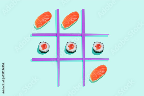 Tic-tac-toe game with salmon sushi maki and nigiri with purple chopsticks on mint green background photo