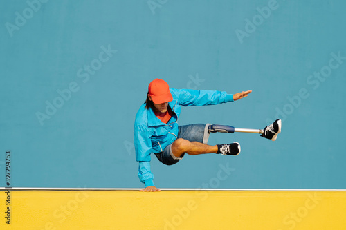 Young disabled man doing handstand against multi colored wall