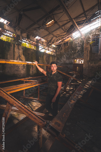 Young man with a camouflage shirt posing in an abandoned building.