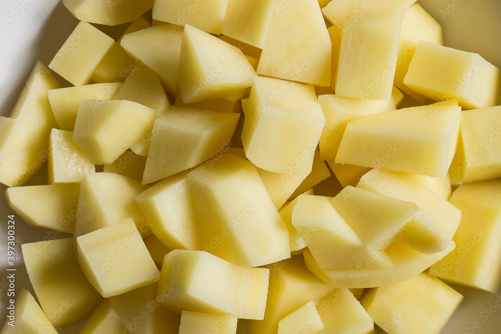A bowl is filled with chopped raw potatoes. Organic texture as a background. A bowl is filled with chopped raw potatoes. Organic texture as a background.