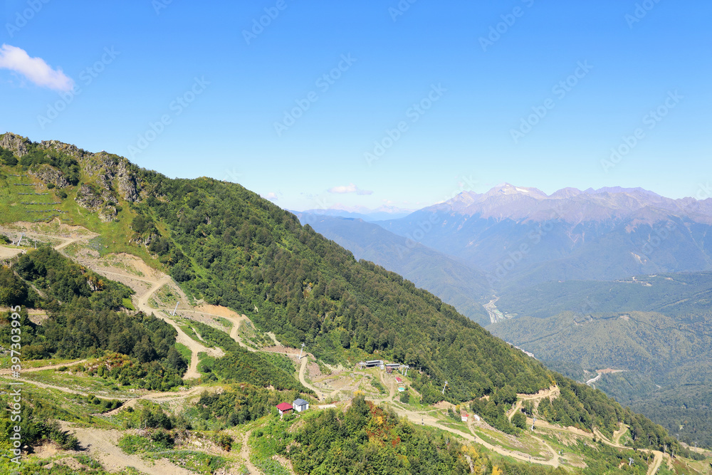 Landscape of green mountain slope with winding road on summer day with copy space