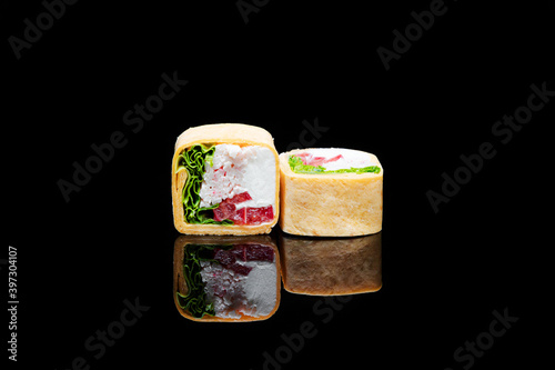 square shaped sushi wrapped in pita bread. on black background