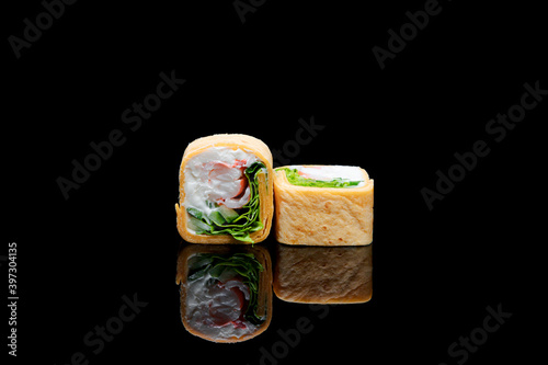 square shaped sushi wrapped in pita bread. on black background