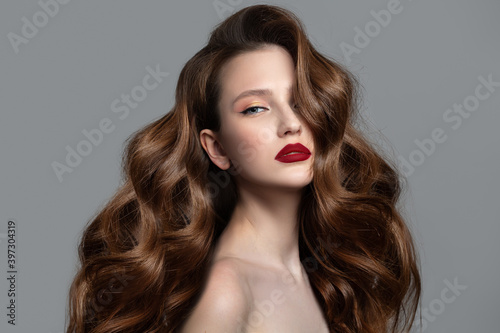 Beautiful woman with red lips and shiny wavy hair. Thick curls and makeup