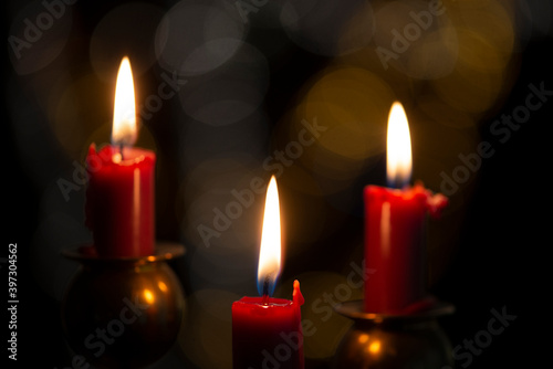 Burning candle on black background with bokeh. Christian Christmas concept.