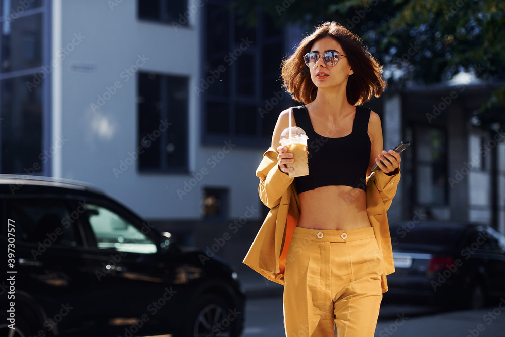 Young fashionable woman in burgundy colored coat at daytime with her car Young fashionable woman in burgundy colored coat at daytime with her car