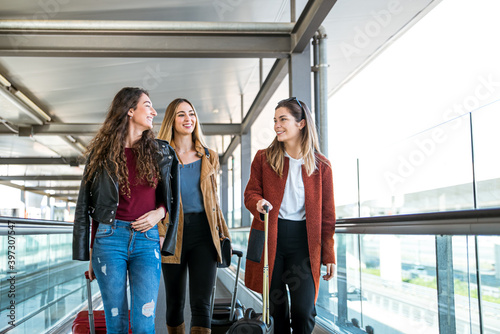 Glad friends with suitcase walking fast by walkway in airport