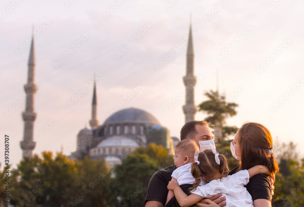 Obraz premium Portrait of happy tourist family in mask in front of Blue Mosque Istanbul, Turkey. Tourism back to Turkey after covid-19 lockdown. Cute mother, father, daughter, son travel together, posing for photo