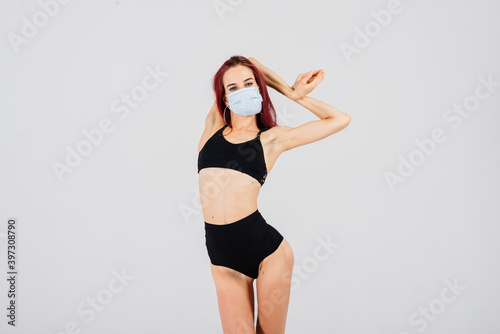 Female dancer in the styles of strip-plastic and pole dance with face mask on light background.