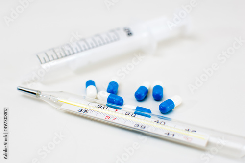 Medical thermometer, syringe and pills isolated on white background
