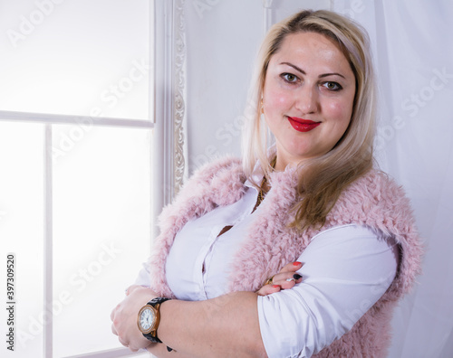 Attractive plump woman standing near window studio portrait. photo