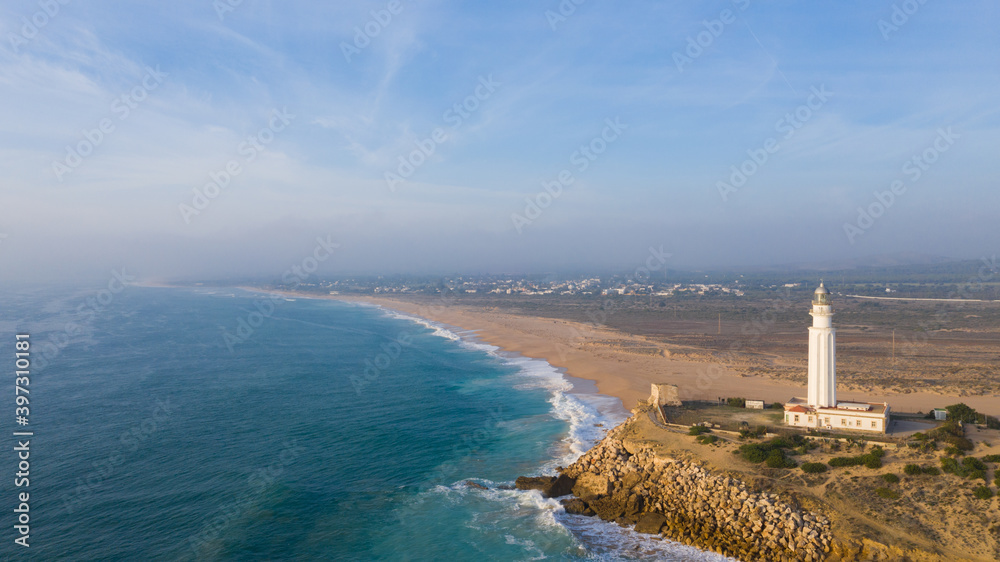 Drone views of the Cape of Trafalgar lighthouse on the Costa de la Luz in Caños de Meca, Cadiz Andalusia, Spain Beach from above on a beautiful day with clouds and the blue sea.