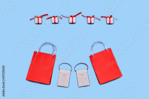 Shopping bags. And white gift boxes with a red satin ribbon bow. Discounts and sales on a blue background.