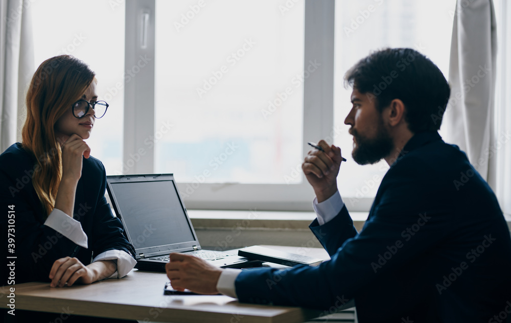 A business man in a suit and a woman communicate at work opposite each other at the table in the office A business man in a suit and a woman communicate at work opposite each other at the table in the office