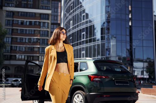 Walks forward from automobile. Young fashionable woman in burgundy colored coat at daytime with her car © standret