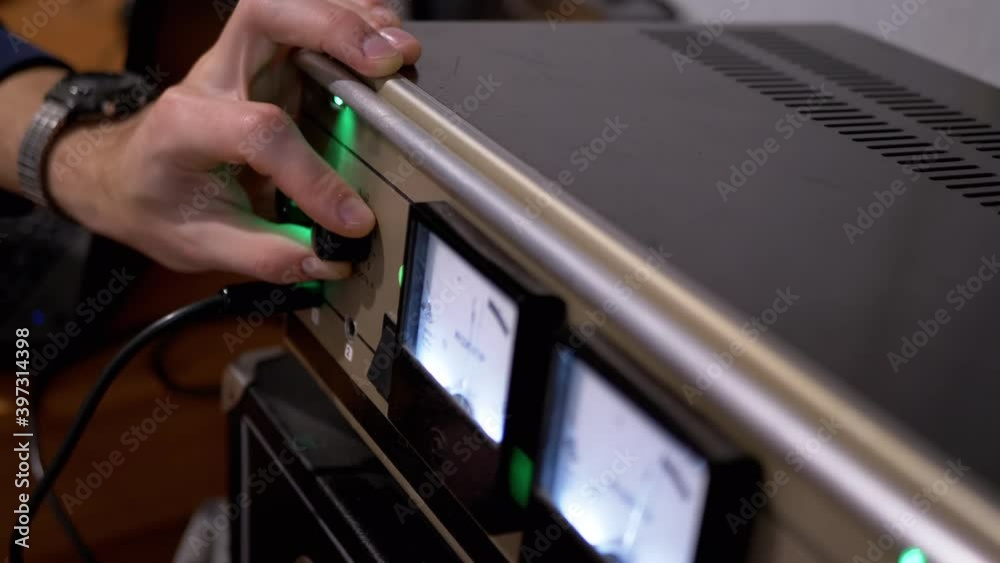 Male Hand Tunes Sound on Retro Stereo Power Amplifier with Illuminated on Dial Male Hand Tunes Sound on Retro Stereo Power Amplifier with Illuminated on Dial