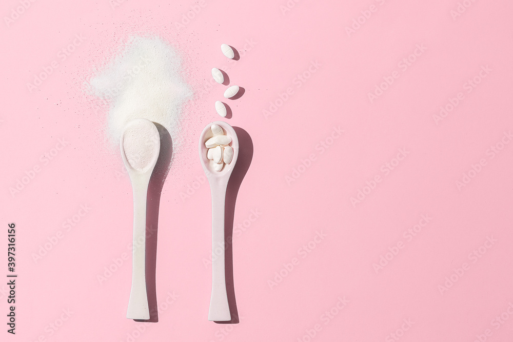 Spoons with collagen on pink background with a copy of space.