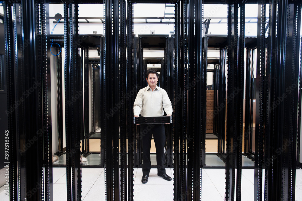 Asian businessman standing in empty server room Asian businessman standing in empty server room