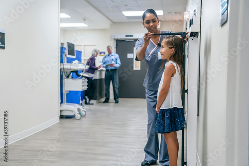 Nurse measuring height of girl in hospital