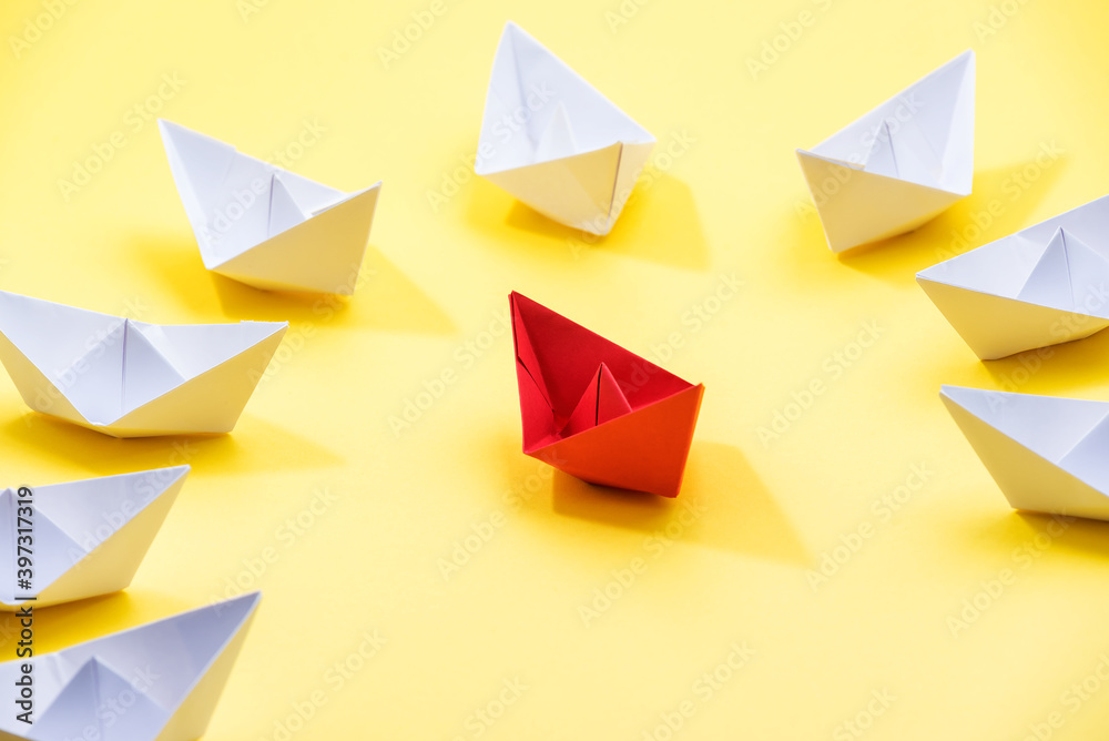 Circle of paper boats, and red colored one standing out from the crowd, leadership and individuality concepts Circle of paper boats, and red colored one standing out from the crowd, leadership and individuality concepts
