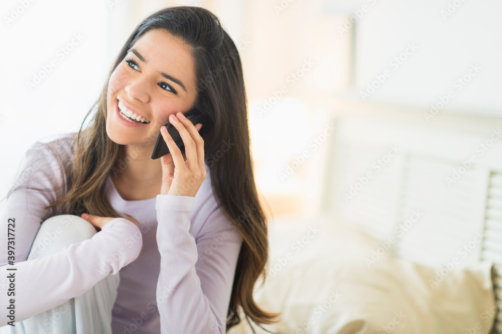 Happy Hispanic woman talking on cell phone in bed Happy Hispanic woman talking on cell phone in bed