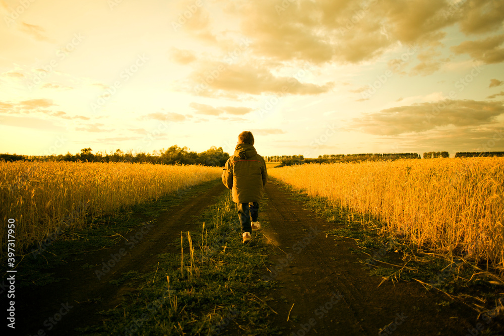 Mixed race child walking on path through rural field Mixed race child walking on path through rural field
