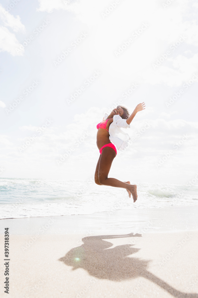 African American woman jumping for joy on beach African American woman jumping for joy on beach