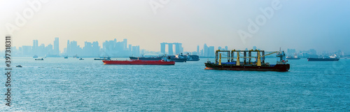 Commercial shipping with Singapore silhouetted in the background in summertime