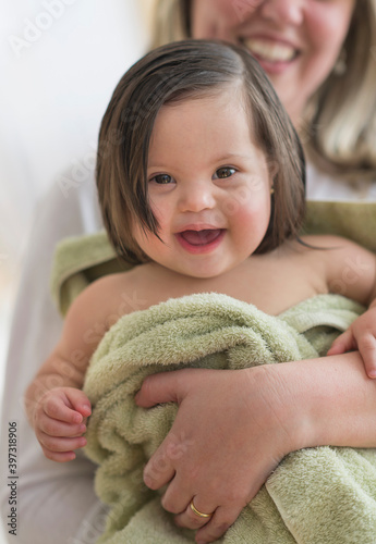 Hispanic mother drying toddler daughter after bath