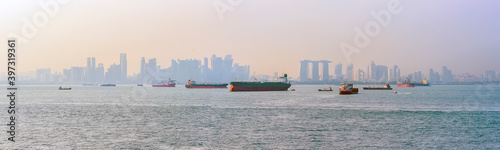 Commercial shipping with Singapore silhouetted in the background at dusk in summertime
