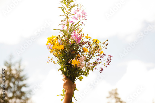 Mari boy holding up bouquet of flowers outdoors