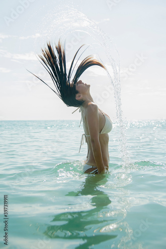 Caucasian woman splashing hair in ocean