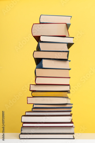 Pile of books stacked on a yellow background with space for copy in a vertical image