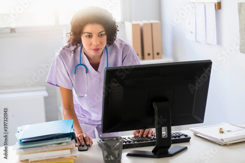 Mixed race nurse using computer in office