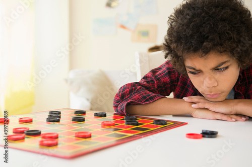 Angry mixed race boy losing game of checkers