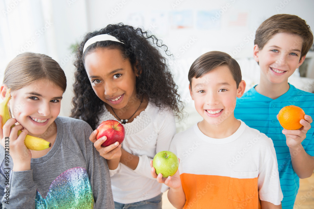 © JGI/Jamie Grill/Blend Images - Smiling children playing with healthy fruit