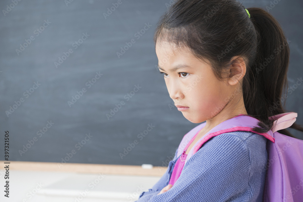 Frowning Vietnamese girl standing in classroom Frowning Vietnamese girl standing in classroom