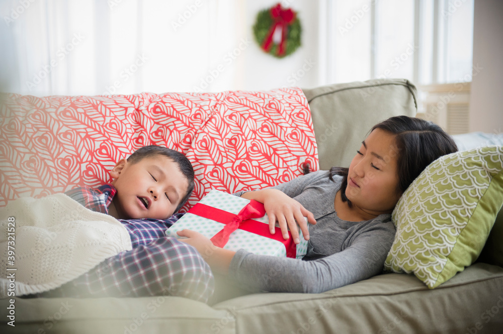 Asian brother and sister napping on sofa with Christmas gift Asian brother and sister napping on sofa with Christmas gift