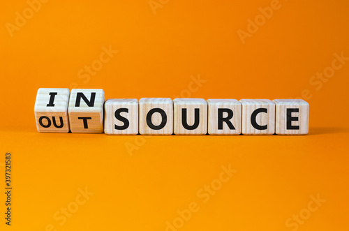 Outsource or insource symbol. Fliped wooden cubes and changed the word 'outsource' to 'insource'. Beautiful orange background, copy space. Business and outsource or insource concept. photo