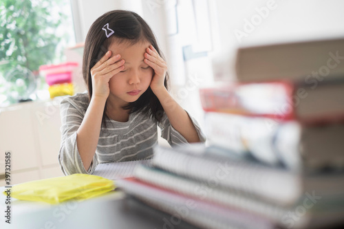 Anxious Chinese student rubbing forehead doing homework